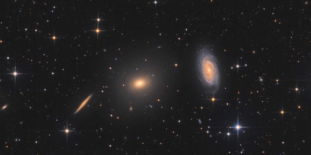 In het midden het elliptische sterrenstelsel NGC5982, rechts daarvan het spiraalvormige sterrenstelsel NGC5985. Deze twee soorten sterrenstelsels blijken zich heel verschillend te gedragen als het gaat om donkere materie.