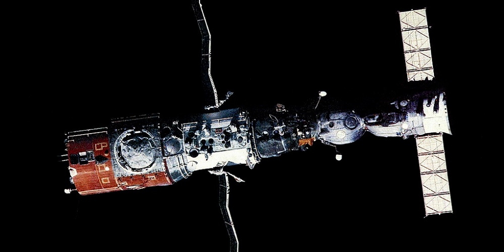 Het Saljoet 6 ruimtestation met een Sojoez ruimtetuig in een baan om de Aarde