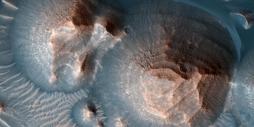 Deze foto toont verschillende kraters in Arabia Terra die gevuld zijn met gelaagd gesteente, vaak blootgelegd in afgeronde heuveltjes. De heldere lagen zijn ongeveer even dik, waardoor ze er trapsgewijs uitzien.