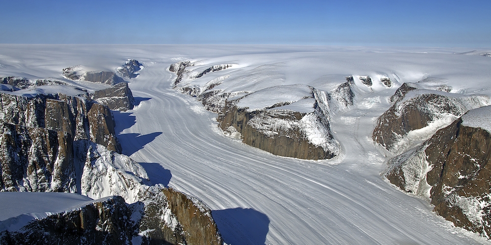 Een gletsjer glijdt door een langgerekte canyon aan de rand van de Sukkertoppen ijskap op ZW-Groenland